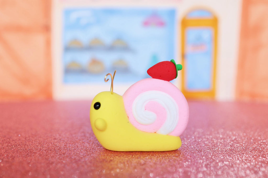 clay snail with a strawberry on a pink surface