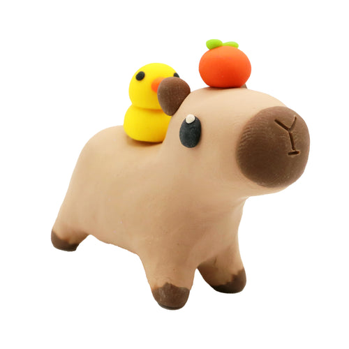 clay capybara with a yellow duck on its back and an orange on its head against a white background