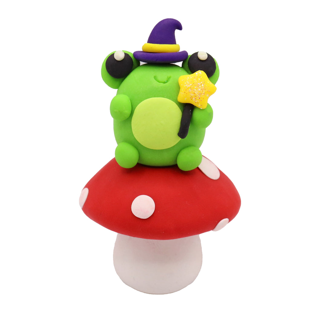 Frog character with a purple hat on a red mushroom with white spots on a white background